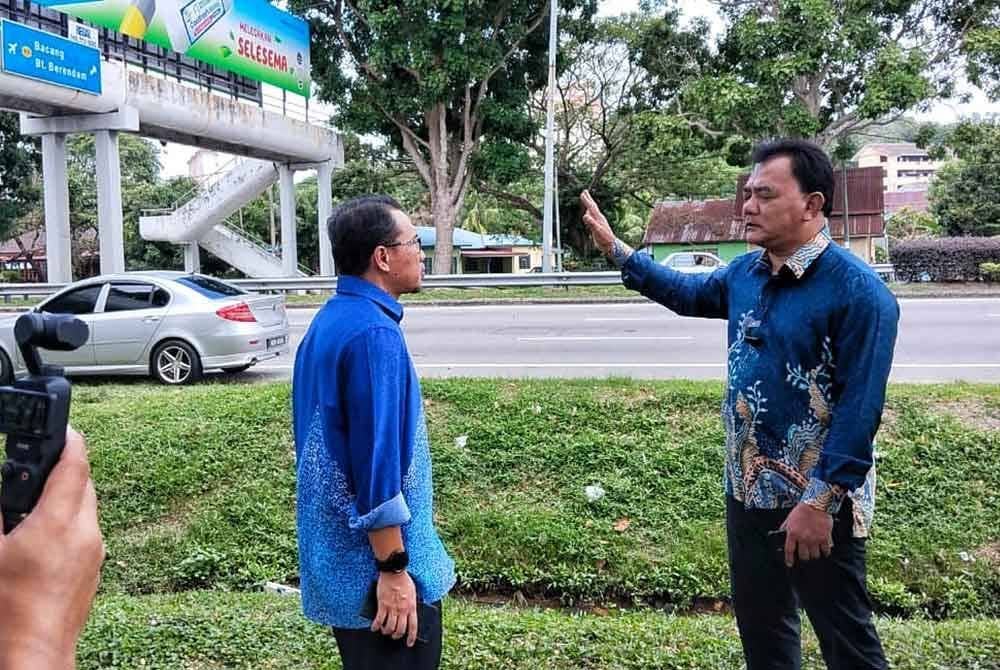 Rahmad (kanan) menunjukkan lokasi yang dipasang kain rentang ajaran sesat itu di Jejantas Peringgit Jaya pada Khamis.