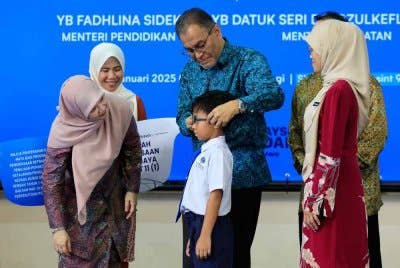 Dr Dzulkefly memakaikan kaca mata pada salah seorang murid yang menerima sumbangan sambil diperhatikan Fadhlina. Foto Bernama