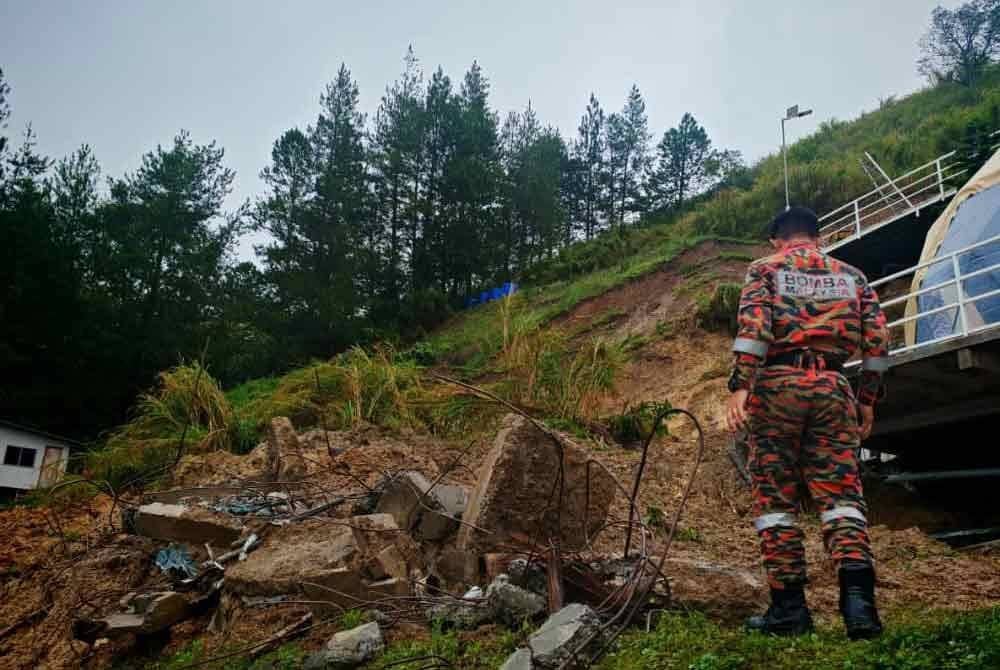 Pasukan bomba melakukan pemantauan di kawasan tanah runtuh yang menyebabkan sebuah rumah inap desa di Kampung Cinta Mata, Kundasang, ranap.