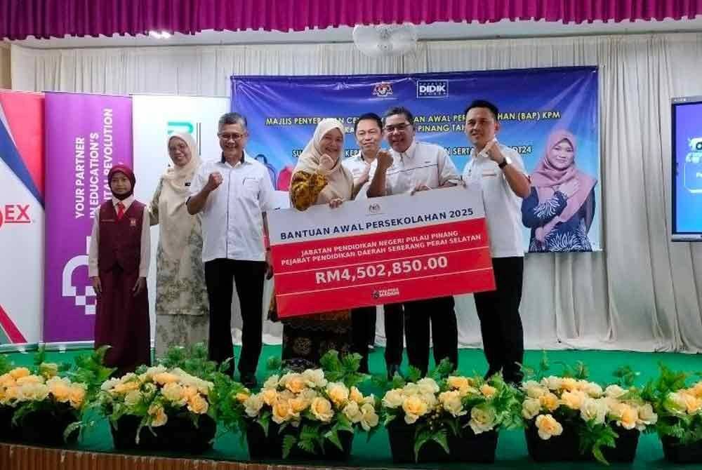 Fadhlina (tengah) menyampaikan replika cek bantuan awal persekolahan di Sekolah Kebangsaan Seri Tasek, di sini pada Jumaat.