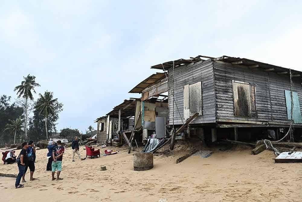 Sebahagian penduduk melihat keadaan rumah yang separuh roboh susulan fenomena ombak besar yang berlaku di Kampung Cacar Lama di sini. - Foto: Bernama.
