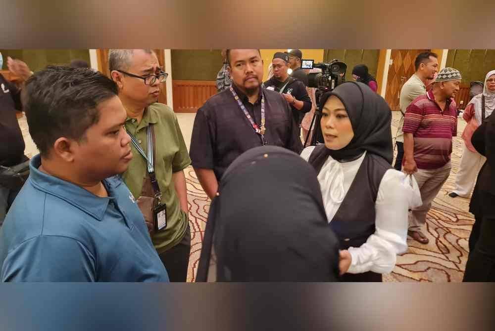 Ena (kanan) membantu para jemaah umrah yang terkandas dalam pertemuan di MOTAC, Putrajaya pada Jumaat.