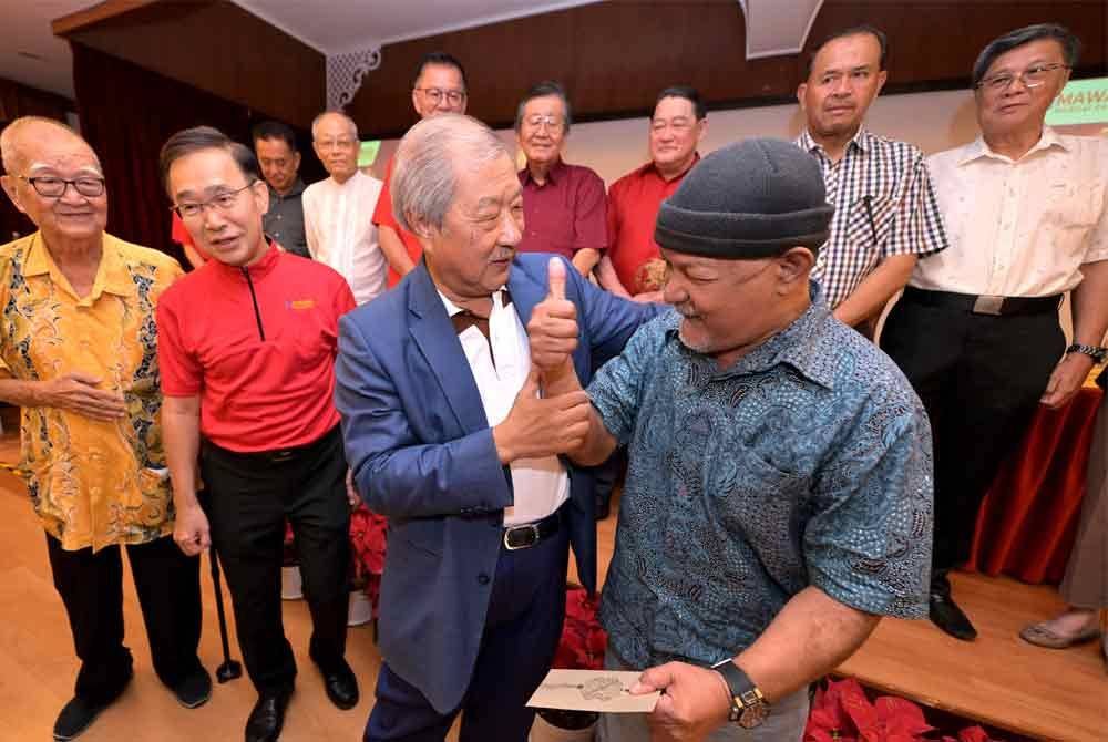 Halaludin (kanan) gembira menerima angpau disampaikan Tian Hock.