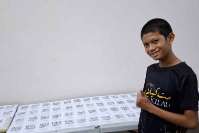 HAMZAH menulis sendiri kad nama khat untuk guru dan kakitangan sekolahnya melibatkan 110 keping keseluruhannya. -Foto: IHSAN FARIZA