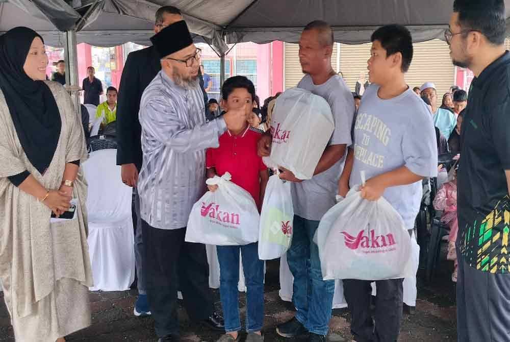 Dr Asmadi (dua dari kiri) menyampaikan bantuan keperluan persekolahan kepada anak salah satu keluarga asnaf terpilih sempena Majlis Pelancaran Program Agihan Zakat Bantuan Persekolahan 2025 di sini pada Sabtu.