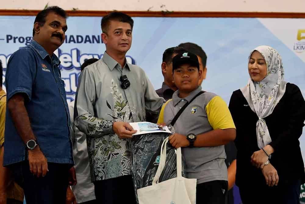 Muhammad Faiz (dua dari kiri) menyampaikan bantuan persekolahan kepada anak-anak nelayan pada Program Madani Anak Nelayan Kembali Ke Sekolah LKIM-PETRONAS di Dewan Pejabat dan Tanah Tanjung Piandang, pada Sabtu. Turut bersama, Pengarah LKIM Perak N Sundralingam (kiri). Foto Bernama