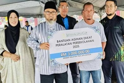 Dr Asmadi (dua dari kiri) menyerahkan replika cek kepada wakil keluarga pemerima sebagai gimik Pelancaran Program Agihan Zakat Bantuan Persekolahan 2025 pada Sabtu.