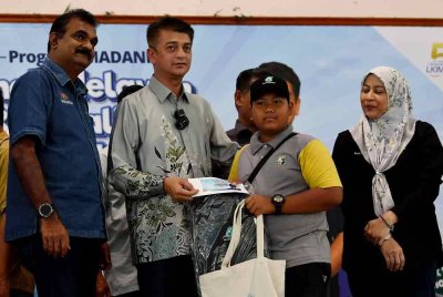 Muhammad Faiz (dua dari kiri) menyampaikan bantuan persekolahan kepada anak-anak nelayan pada Program Madani Anak Nelayan Kembali Ke Sekolah LKIM-PETRONAS di Dewan Pejabat dan Tanah Tanjung Piandang, pada Sabtu. Turut bersama, Pengarah LKIM Perak N Sundralingam (kiri). Foto Bernama