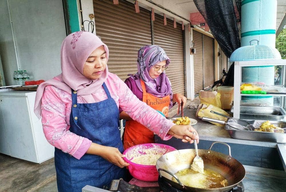 Norkhiriah (kiri) dan Haslizawati tekun memasak jemput-jemput yang ditempah pelanggan. Foto ihsan orang awam
