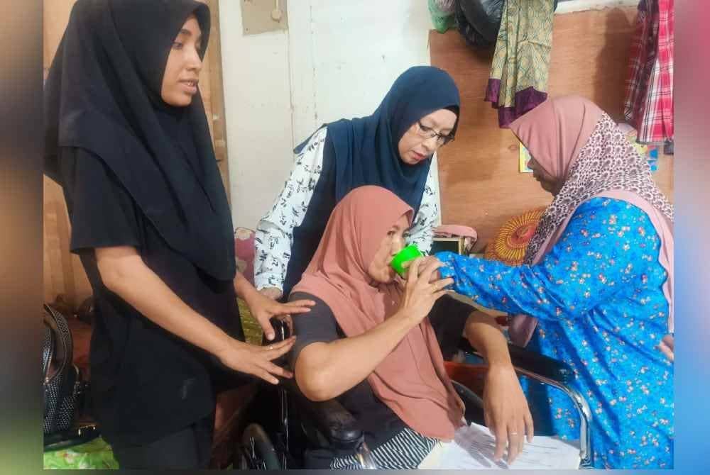 Sharifah dibantu oleh Zaliza untuk minum sambil diperhatikan oleh Noor Farhana (kiri) dan Zuraini (dua kiri) di Kampung Empa, Jitra pada Isnin.