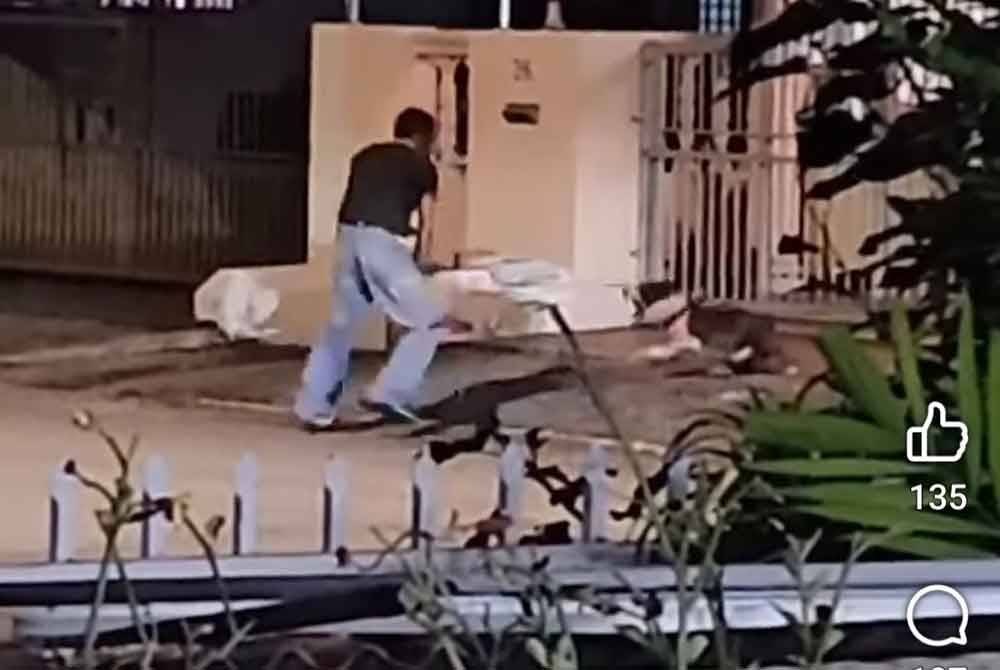 Tangkap layar video tular menunjukkan seorang lelaki bertindak memukul anjing peliharaannya menggunakan besi.