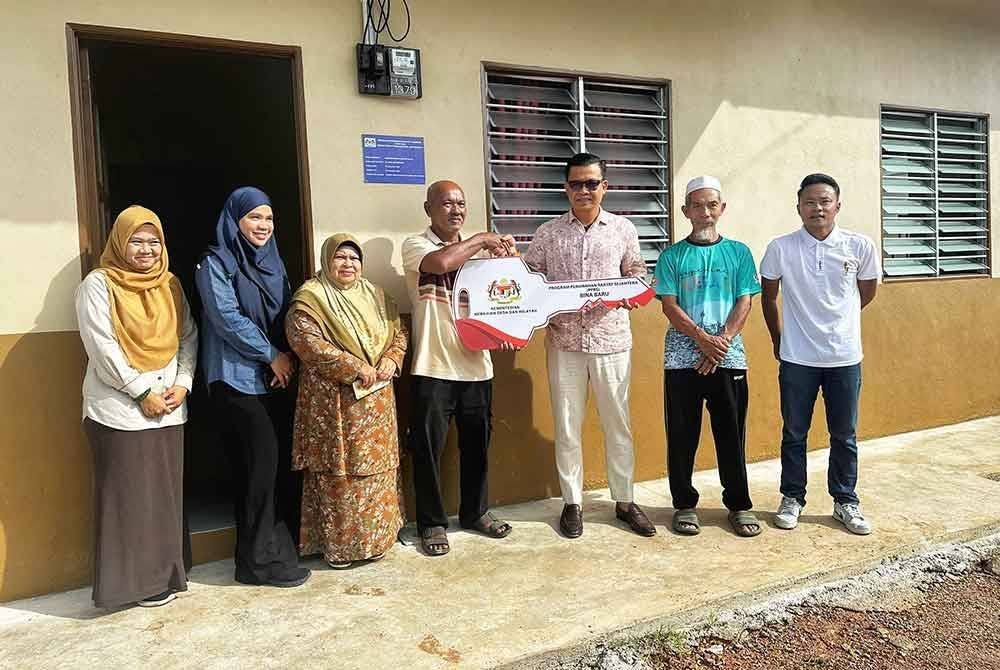 Mohd Nizam (tiga dari kanan) menyampaikan replika kunci kepada Mohd Nazi di kediamannya di Kampung Pida 5 Ayer Hitam.