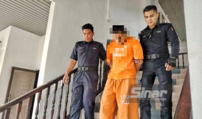 Suspek berusia 41 tahun (tengah) ketika dibawa keluar dari Mahkamah Majistret Melaka, pada Isnin.