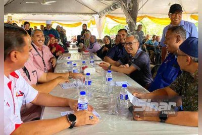 Fahmi (duduk, tiga dari kanan) beramah mesra dengan orang ramai yang hadir Program Ihsan Komuniti Madani di Kampung Baru Nelayan, Tumpat pada Isnin. FOTO: SINAR HARIAN