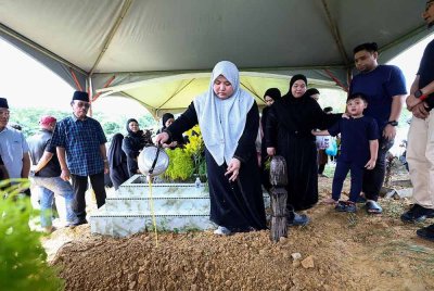 Nurhafizah Fatin menyiram air ke atas pusara bapanya Ahli Dewan Undangan Negeri (ADUN) Sungai Sibuga, Datuk Mohamad Hamsan Awang Supain selepas selamat dikebumikan di Tanah Perkuburan Islam Taman Bintang Baru Rancangan Sungai Manila pada Isnin. Foto Bernama