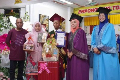 Norhaidah (dua dari kiri) dan Hirwan (kiri) meraikan kejayaan Hazim (tengah) yang terpilih menerima anugerah cemerlang kokurikulum SK Seri Makmur pada Khamis.
