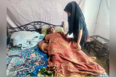 Noor Farhana (kanan) akan menguruskan ibunya pada setiap pagi di rumah mereka di Kampung Empa, Jitra sebelum pergi bekerja sebagai pembantu kedai makan.