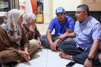 Megat Zulkarnain (kanan) menyantuni keluarga OKU, Ahmad Nor Al Faizan Jusoh di Kuala Ibai pada Isnin. Foto Bernama