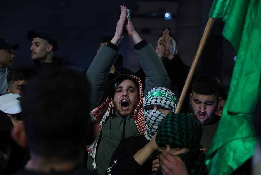 Penduduk Palestin melaungkan slogan kemenangan ketika menyambut kepulangan 90 tahanan. - Foto: AFP