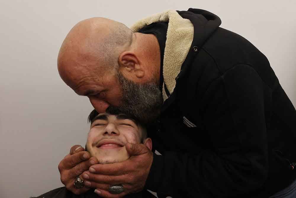 Bapa saudara kepada banduan Palestin berusia 17 tahun, Qassem Jaafra mencium dahinya sebaik tiba di rumahnya di kejiranan Silwan di timur Baitulmaqdis selepas dibebaskan pada awal pagi Isnin bersama 90 banduan Palestin yang lain. Foto: AFP
