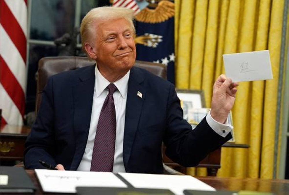 Trump tersenyum sambil menunjukkan surat tinggalan Biden kepadanya yang ditemukannya dalam laci meja di Pejabat Oval, Washington, pada Isnin. Foto AP