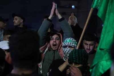Penduduk Palestin melaungkan slogan kemenangan ketika menyambut kepulangan 90 tahanan. - Foto: AFP