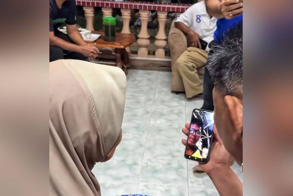 Abdul Razak (kanan) ketika membuat panggilan video dengan Rosenizam ketika berkunjung ke rumah mangsa pada malam Selasa.