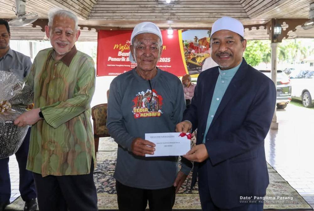 Mohd Nassuruddin (kanan) menyampaikan sumbangan kepada pengayuh beca sempena Majlis Penyampaian Bantuan Pengayuh Beca Negeri Kelantan 2025. Foto MB