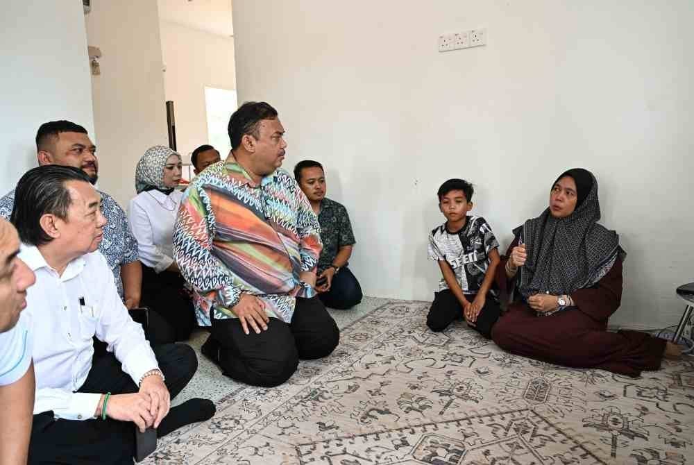 Setiausaha Politik kepada Perdana Menteri, Datuk Azman Abidin (dua dari kiri) menyantuni ibu mangsa, Ruziah Fuad, 47, (kanan) selepas dua anaknya maut dalam kejadian tanah runtuh tahun lalu, semasa melakukan lawatan di Kampung Bukit Apit pada Rabu. Foto Bernama