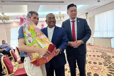 Sanusi (tengah) menyerahkan sumbangan Tahun Baharu Cina kepada penerima disaksikan Wong Chia Zhen (kanan) di Wisma Darul Aman pada Rabu.