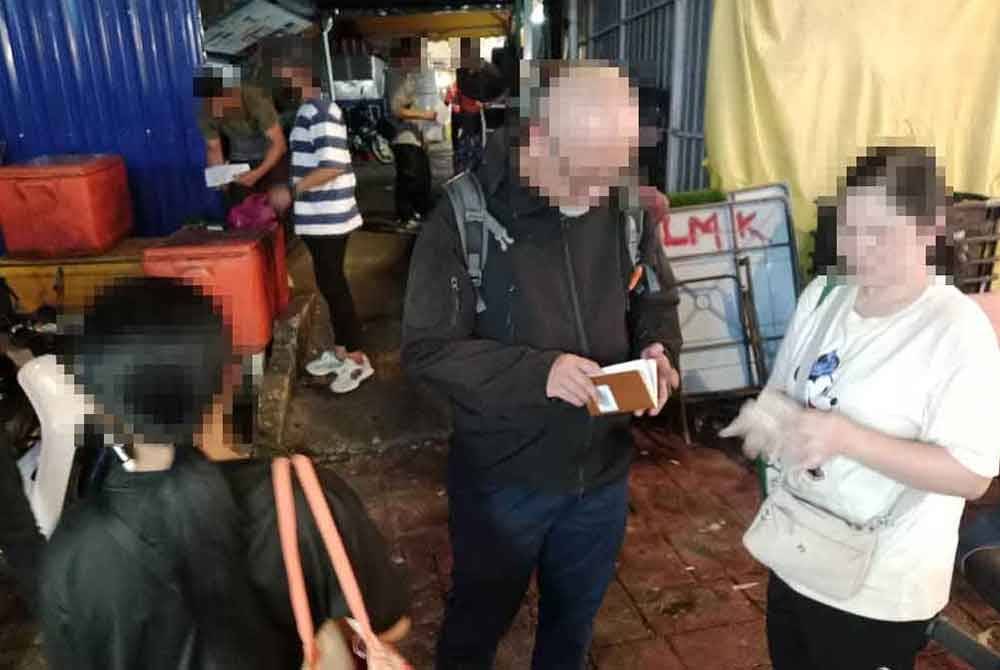 Pegawai Imigresen Kuala Lumpur memeriksa dokumen warga asing yang ditahan dalam Ops Sapu sekitar kawasan Jalan Alor pada Rabu.