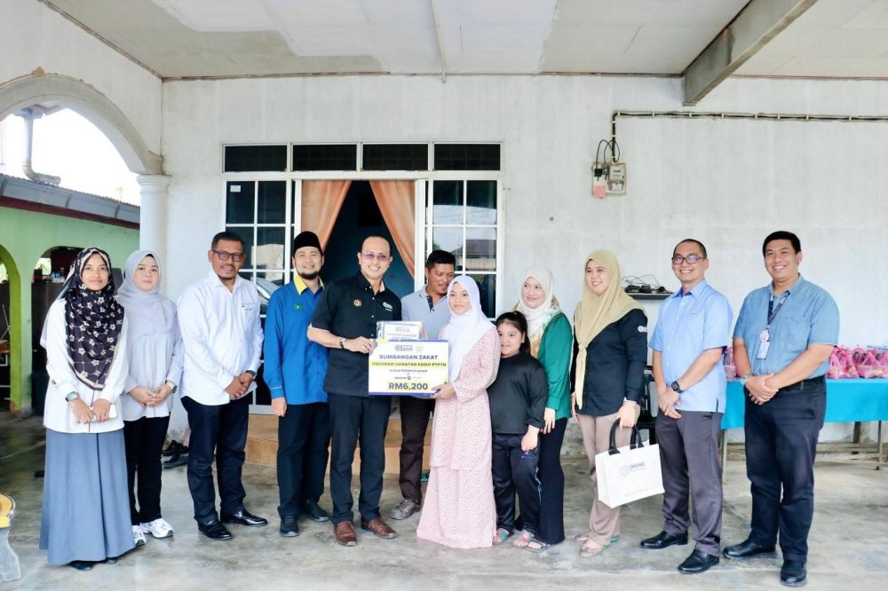 Ketua Eksekutif PTPTN, Ahmad Dasuki Abdul Majid (lima dari kiri) menyerahkan sumbangan bantuan persekolahan dan simpanan dalam Simpan SSPN  Prime kepada pelajar MRSM Arau, Anis Nur Fatihah Ahmad Syahid di kediamannya di Kampung Gial,Kangar, di sini, pada Rabu.