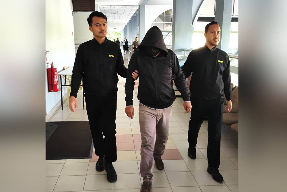 Arwan Asrol (tengah) diiring pegawai SPRM ketika hadir ke mahkamah pada Khamis.