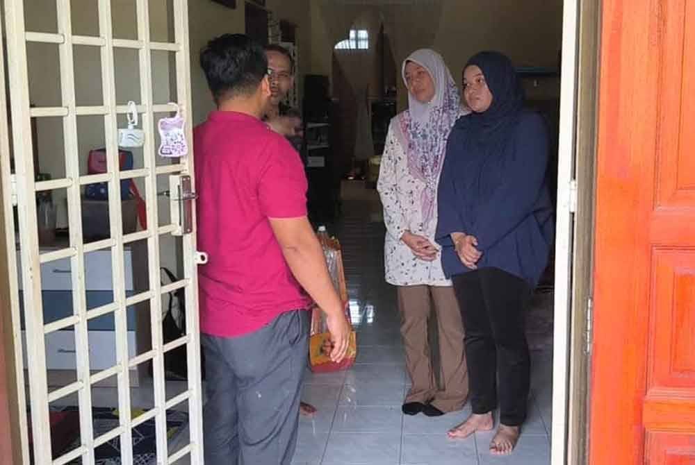 Wan Mahussin (kiri) ketika tiba di rumah keluarga mangsa pukul di Kuala Ibai, Kuala Terengganu pada Rabu.