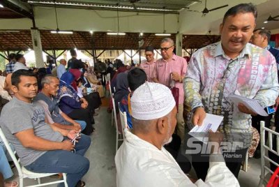 Azman (berdiri) menyampaikan sumbangan pada Program Bantuan One Off Perdana Menteri anjuran bersama Pertubuhan Masyarakat Madani Gaul Ipoh (MMGI) di Tanah Merah pada Khamis.