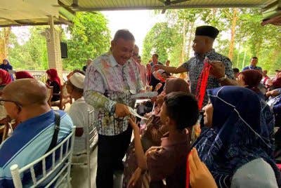 Azman (kiri) menyampaikan sumbangan pada Program Bantuan One Off Perdana Menteri anjuran bersama Pertubuhan Masyarakat Madani Gaul Ipoh (MMGI) di Tanah Merah pada Khamis.