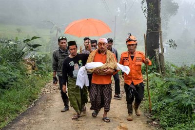 Seorang ayah mendukung anak perempuannya yang berusia satu tahun setengah yang meninggal dunia akibat tanah runtuh. Foto AFP