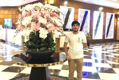 Muhammad Tasnim bersama bunga yang digubah di lobi sebuah hotel bertaraf lima bintang.