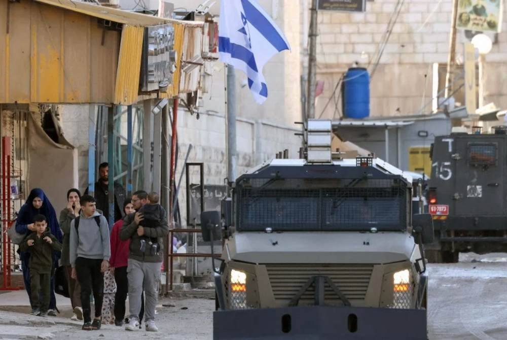 Pasukan Israel dalam kenderaan berperisai melintasi penduduk Palestin semasa serbuan tentera di Jenin. Foto AFP
