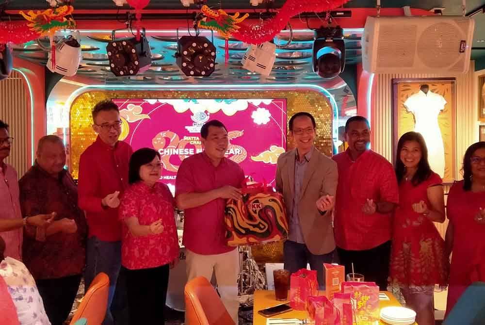 Nigel (tiga dari kanan) menyampaikan cenderahati kepada Sze Yee sempena Majlis Makan Malam Tahun Baharu Cina MATTA Cawangan Perak di Hard Rock Cafe di sini pada Khamis.