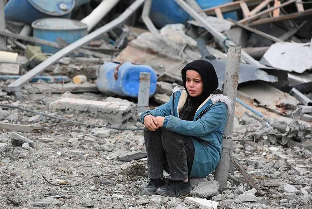 Seorang kanak-kanak Palestin menangis ketika dia duduk di tengah -tengah runtuhan bangunan di kejiranan yang hancur di bandaraya Rafah di selatan Gaza. Foto AFP