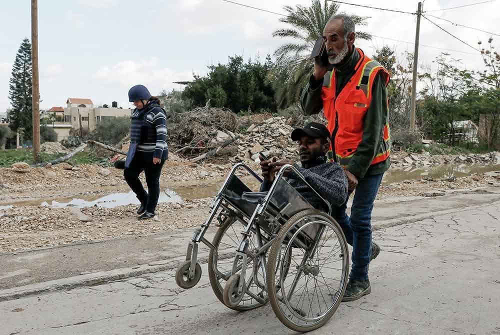 Anggota perubatan Palestin membantu orang kurang upaya berpindah dari kem pelarian Jenin.