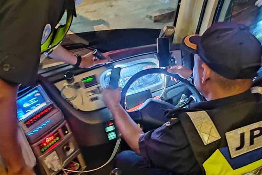 Dua anggota penguat kuasa JPJ Melaka sedang melakukan pemeriksaan teknikal pada sebuah bas ekpres.