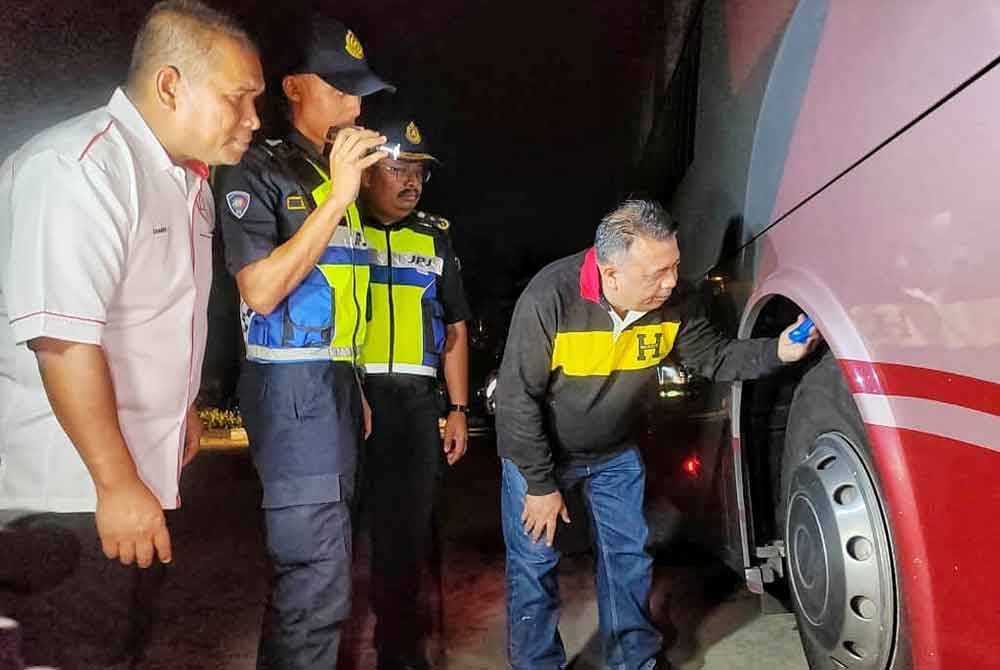 Hameed (kanan) ketika memeriksa tayar sebuah bas ekpres dalam operasi itu.