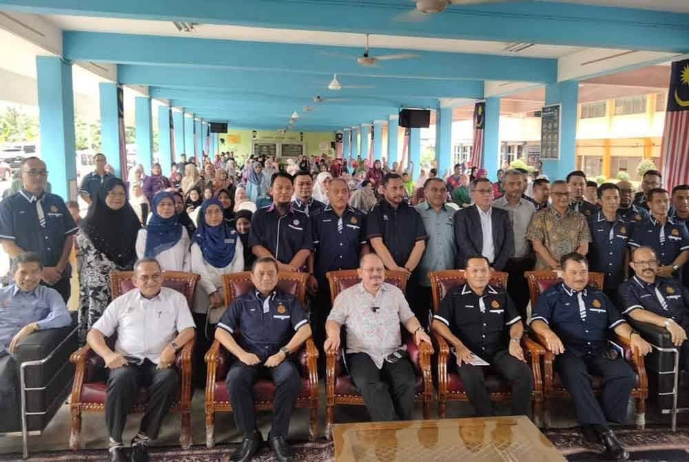Shamsul Iskandar (duduk, tengah) bergambar bersama tetamu dan penduduk yang menghadiri Program Majlis Sumbangan Skuad Ihsan Madani JPJ dan Pakaian Seragam Sekolah Kepada Mangsa Banjir pada Sabtu.