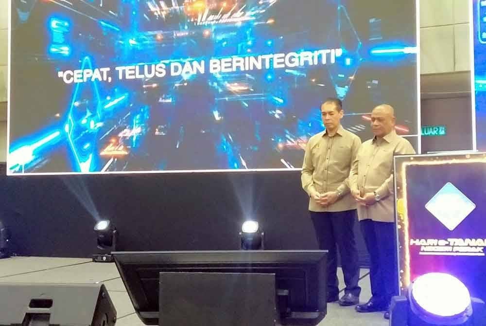 Mohamad Fariz (kiri) mengiringi Saarani ketika merasmikan Program Hari e-Tanah Negeri Perak di Stadium Indera Mulia di sini pada Sabtu.