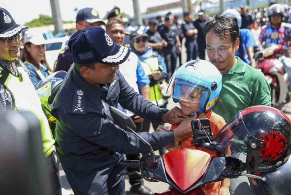 Hussein (dua dari kiri) mengagihkan topi keledar percuma kepada penunggang motosikal sempena Kempen Keselamatan Jalan Raya Sempena Op Selamat Tahun Baru Cina 2025 Peringkat Kontinjen Selangor di Plaza Tol PJS 2 hari ini. Foto Bernama
