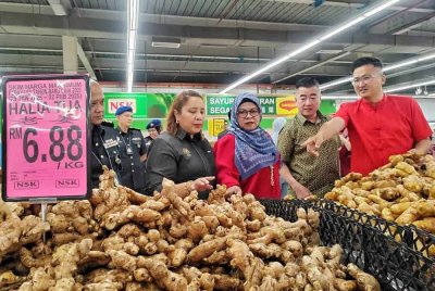 Norena (dua dari kiri) pemeriksaan harga barang sempen, Mana Tahun Baharu Cina di sebuah pasar raya di Cheng pada Sabtu.