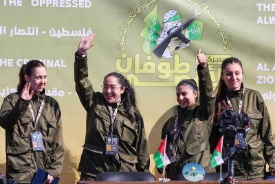 Keempat-empat tentera yang dibebaskan itu tersenyum dan melambai di atas pentas di Dataran Palestin di Gaza City ketika mereka diserahkan kepada wakil ICRC. Foto AFP