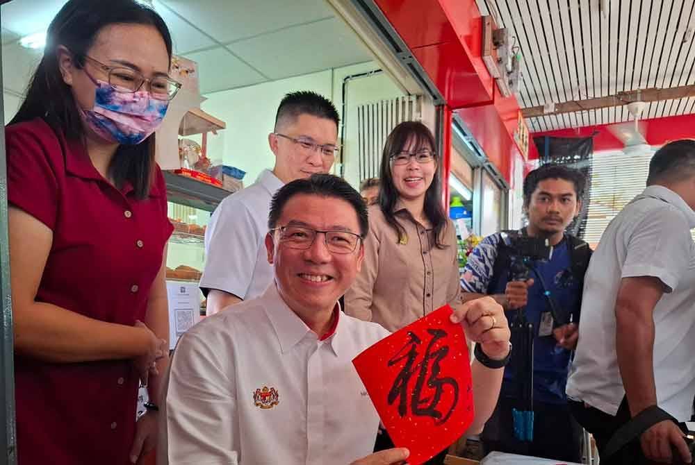 Kor Ming menunjukkan tulisan kaligrafi yang dihasilkan ketika sesi lawatan ke Pasar Taman Canning, Ipoh pada Ahad.
